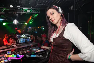 DJ Selina Style at the decks in headphones, the dance floor behind her
